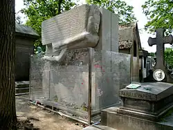 Oscar Wilde's tomb behind a glass protective barrier, showing the carved stone sphinx figure