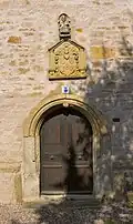 Side entrance of the church with coat of arms