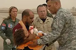 A U.S. Air Force airman, a U.S. Army soldier and a Turkish Air Force pilot transport an Iraqi child to safety during a humanitarian airlift effort