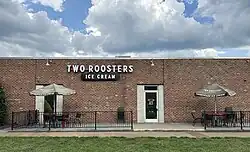 A one story brick building with a fenced in seating area in the front shaded by umbrellas