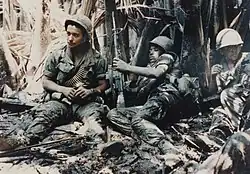 Three American soldiers lying in mud in Vietnam in 1968