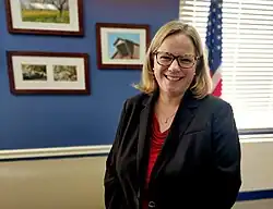 Photo of Undersecretary Moffitt in her office in front of American flag and pictures of her family's organic walnut farm