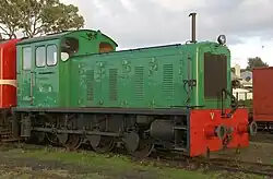 A green 0-6-0 diesel locomotive 'V8' sits on a track just outside of the workshops in queenscliff