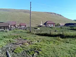 A picture of a hill in Aryshparovo with houses on them with a fence in front of the houses