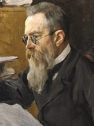 Head of a man with dark greying hair, glasses and a long beard