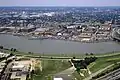 Aerial photograph of the Washington Navy Yard with a destroyer at dock, the Anacostia River in the foreground and Capitol Hill in the background.