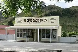 An old-fashioned storefront with a sign reading McCluggage Bros. in a rural environment