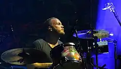 Champion on stage with his drums, wearing a black shirt