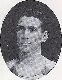 A black and white photograph of a head shot of a Caucasian man with hair slicked to the side.