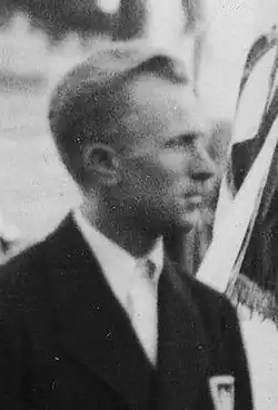 A young man visible from the chest up, looking to his left, and wearing a suit and tie