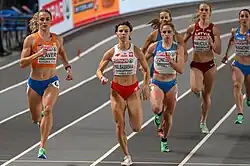 Frontal photo of six runners on grey indoor tracks