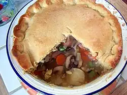 A cooked pie on a white plate, with one quarter removed