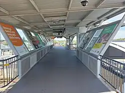 A footbridge with a roof covering it and advertisements on the walls