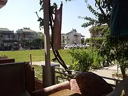View from a house porch of a big lawn with several houses beyond