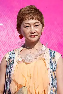 waist up portrait of Watanabe in peach shoulderless dress, facing toward camera