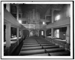 The interior of Old North Church, showing box pews on the ground floor and the balcony. Includes view of organ pipes.