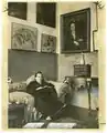 Stein sitting in front of paintings at 27 rue de Fleurus, including Picasso's painting of her.